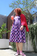 Toomi Tess The Hippo dress, full length outdoors, worn with a red cardigan and pink shoes